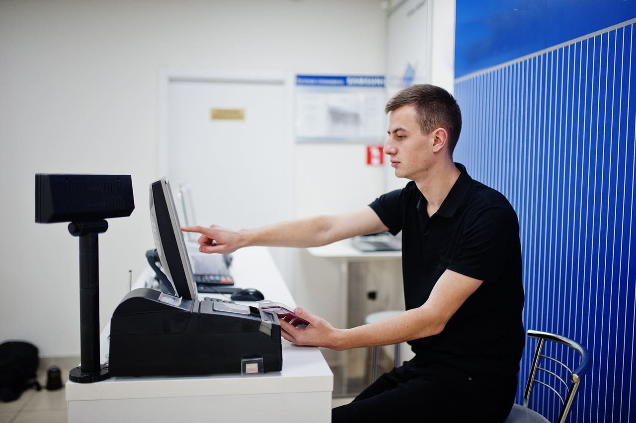 An installer sets up a till and a receipt printer in a store